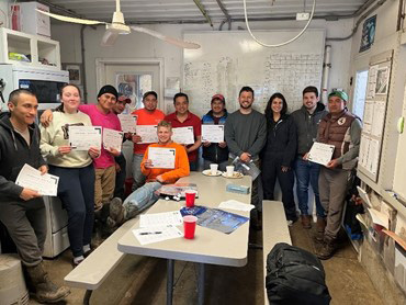 A group of people who are holding up certificates for completing a training.